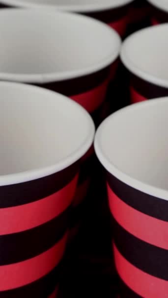 Ряд червоно-чорний одноразовий паперовий стаканчик для кави або гарячого напою на темному фоні обертається повільно . — стокове відео