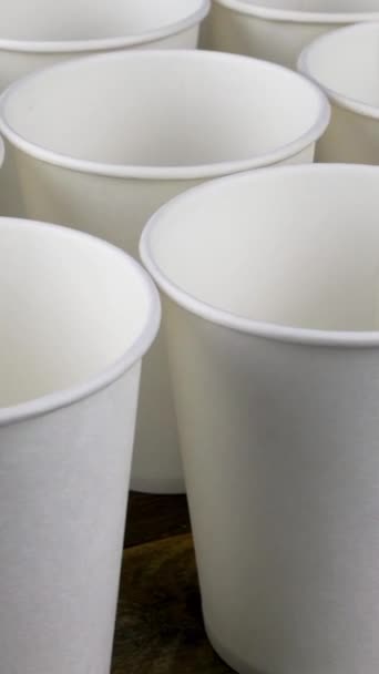 Reihe weißer Einweg-Pappbecher für Kaffee oder Heißgetränk auf dunklem Hintergrund drehen sich langsam. — Stockvideo