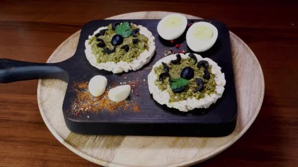 Kue beras panggang dengan menyebarkan saus pesto hijau dan telur rebus berputar perlahan-lahan pada memotong papan. — Stok Video