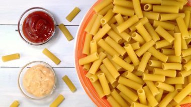 Pişmemiş çiğ italyan rigatoni makarnası. Tabakta yavaşça dönüyor..