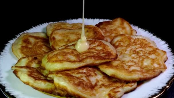집에서 튀겨 만든 갓 튀긴 달콤 한 팬케이크가 접시 위에서 회전하면서 응축 우유를 부어 놓은 모습. — 비디오