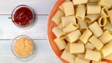 Pişmemiş çiğ İtalyan Paccheri makarnası. Tabakta yavaşça dönüyor..