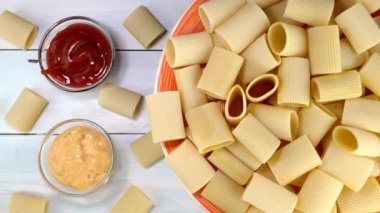 Pişmemiş çiğ İtalyan Paccheri makarnası. Tabakta yavaşça dönüyor..