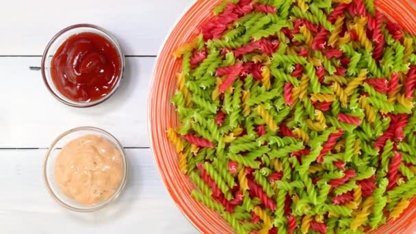 Multicolored uncooked raw italian fusilli pasta rotating slowly on turntable in dish. — Vídeo de stock