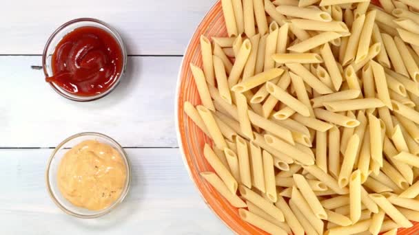 Nevařené syrové italské těstoviny penne pomalu rotující na točném stole v misce. — Stock video