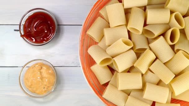 Άψητα ωμά ιταλικά paccheri ζυμαρικά περιστρέφονται αργά στο πικάπ στο πιάτο. — Αρχείο Βίντεο