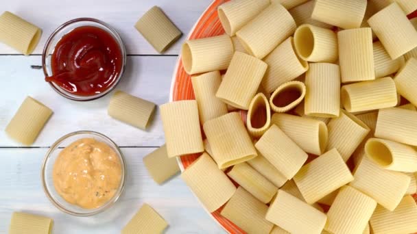 Uncooked raw italian paccheri pasta rotating slowly on turntable in dish. — стоковое видео