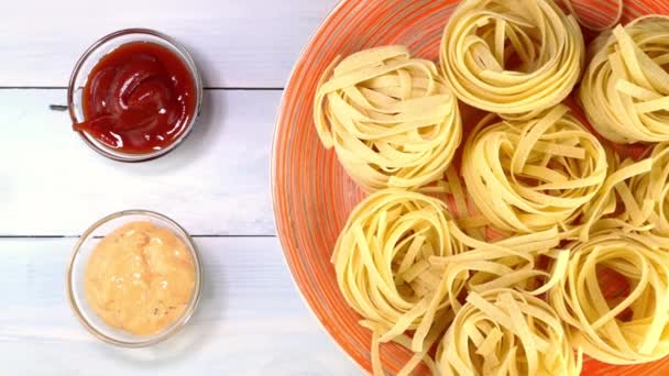 Nevařené syrové italské tagliatelle těstoviny se pomalu otáčejí na točném stole v misce. — Stock video