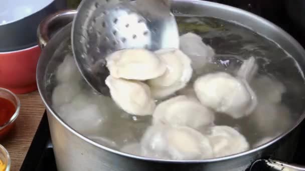 Dumplings boiled in hot water in saucepan with bay leaf on domestic kitchen. — Vídeo de stock