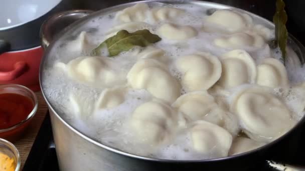 Dumplings hervidos en agua caliente en cacerola con hoja de laurel en la cocina doméstica. — Vídeos de Stock