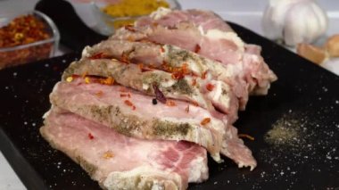 Cook rubs fresh raw pork fillet with grated garlic and spices for making chops.