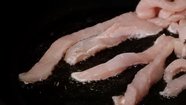 Krájené kousky kuřecího řízku, smažené na pánvi v rostlinném oleji s rozmarýnem a kořením. — Stock video