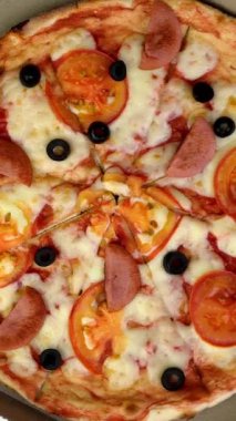 Domatesli, sosisli, mozarellalı ve karton kutuda zeytinli taze yuvarlak pizza yavaşça döner..