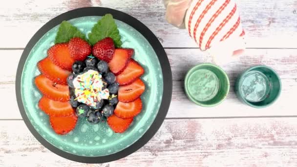 Efterrätt med jordgubbar och blåbär med yoghurt eller vispgrädde roterar långsamt på skivtallriken. — Stockvideo