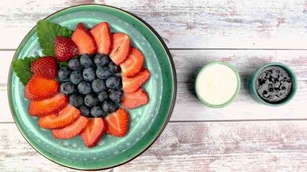 Dessert avec fraises et bleuets au yaourt ou crème fouettée tourner lentement sur la plaque tournante. — Video