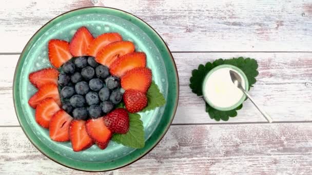 Postre con fresas y arándanos con yogur o crema batida rotar lentamente en el plato giratorio. — Vídeo de stock