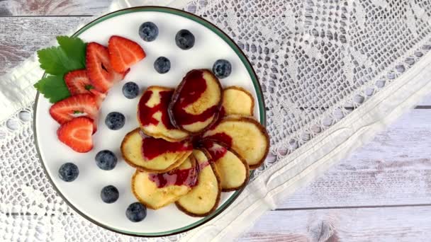 Pannkakor med jordgubbar, blåbär som häller med sylt roterar långsamt på skivtallriken. — Stockvideo