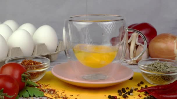 Разбитые сырые куриные яйца наливают в прозрачную стеклянную миску в кухонном столе. — стоковое видео