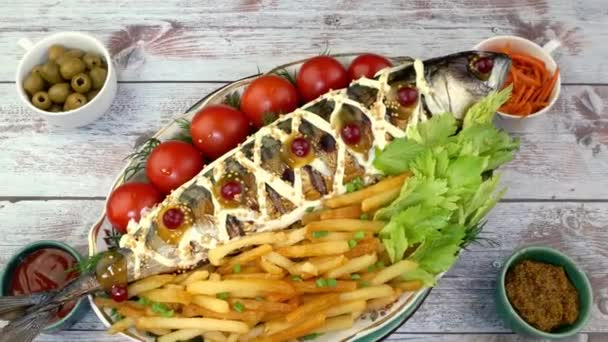 Gebratener Makrelenfisch mit Pommes frites, Tomaten und Sellerieblättern rotiert langsam auf Plattenteller. — Stockvideo