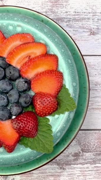 Vegetarisches gesundes Dessert mit Erdbeeren und Blaubeeren rotieren langsam auf dem Plattenteller. — Stockvideo