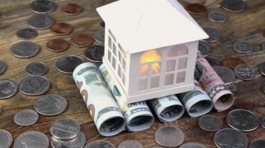 Ev, Amerikan dolarlarının üstüne yığılmış banknotlar ve bir sürü bozuk para. Gayrimenkul ve gayrimenkul yatırımları için ev parası ve mali varlıkların tasarrufu. Yakın plan..