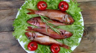 Tütsülenmiş deniz balığı salata yaprakları ile domates ve biberiye servis edilir ve beyaz tabakta yavaşça döner. Lezzetli Akdeniz yemekleri. Üst Manzara. Yakın plan..