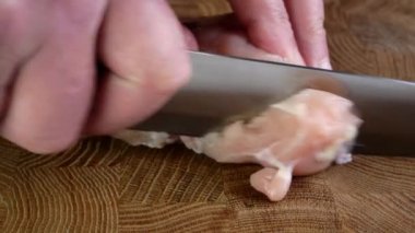 Bıçaklı insan eli çiğ tavuk dilimleri ya da kesme tahtasındaki hindi göğsü filetosu. Ev mutfağında hazırlanmış lezzetli bir yemek. Yakın plan..