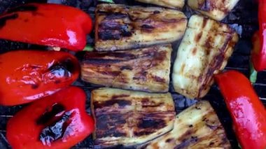 Izgarada kızartılmış kırmızı dolmalık biber ve patlıcan, yakın plan dumanlı vejetaryen yemeği. Vejetaryen ızgara yemeği. Kamera döndürme, seğirme, el kamerası. Yakın plan..