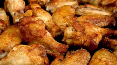 Many fried, sliced chicken wings, with crispy crust rotate slowly. Tasty healthy dinner on domestic kitchen. Close up.