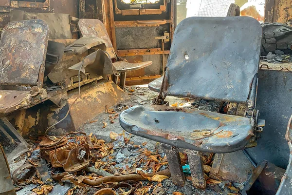 Burnt seats in abandoned burned out vehicle, of charred interior. Fire damaged on city street, vandalism or fighting during war. Close up.
