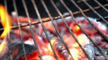 Wooden firewood and charcoal burn fire with hot orange flames, sparks and smoke in grill stove. Preparation grill for cooking outdoors on metal grate. Foreground focus. Close up.