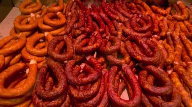 Many smoked sausage types lying in display-type fridge on supermarket counter for sale. Grocery department on market showcase. Close up.