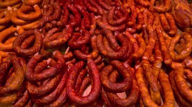 Many smoked sausage types lying in display-type fridge on supermarket counter for sale. Grocery department on market showcase. Close up.