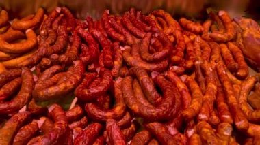 Many smoked sausage types lying in display-type fridge on supermarket counter for sale. Grocery department on market showcase. Close up.