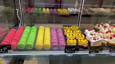 Süpermarkette satılık kek ve makaronlu şekerlemeler sergileniyor. Pastanenin vitrinindeki tatlıların çeşitleri. Kapat..