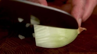 Mutfakta keskin bir bıçakla ahşap mutfak tahtasına ince beyaz soğan dilimlemek. Kapat..