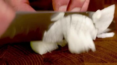 Mutfakta keskin bir bıçakla ahşap mutfak tahtasına ince beyaz soğan dilimlemek. Kapat..