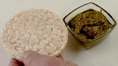 Pirinç kekinin üzerine yeşil pesto sosu ve hazırlama sandviçi. Lezzetli ev yapımı vejetaryen ve vejetaryen yemekleri. Ağır çekim. Kapat..