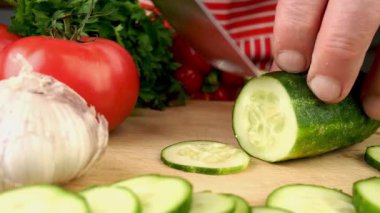 Evcil mutfağın tahta kesme tahtasındaki keskin bıçaklı salatalıkla dilimlenmiş. Hazırlık lezzetli vejetaryen ve vegan sağlıklı sebze salatası. Ağır çekim. Kapat..