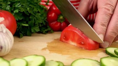 Evcil mutfağın tahta kesme tahtasına keskin bıçaklı domates dilimlemek. Hazırlık lezzetli vejetaryen ve vegan sağlıklı sebze salatası. Ağır çekim. Kapat..
