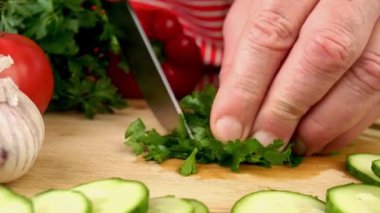 Maydanozu keskin bıçakla dilimlemek yerli mutfağın tahta kesme tahtasına. Hazırlık lezzetli vejetaryen ve vegan sağlıklı sebze salatası. Ağır çekim. Kapat..