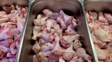 Marketteki kasap tezgahında, yiyecek bölümünde et konteynerinde çiğ tavuk parçaları satılıyor. Kapat..