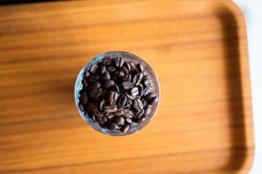 Bardaktaki kahve çekirdekleri ahşap arka planda..