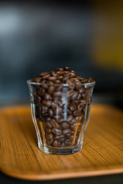 Bardaktaki kahve çekirdekleri ahşap arka planda..