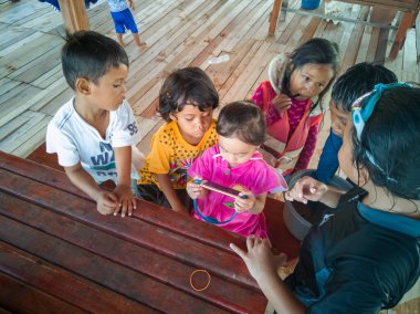 Semporna, Malezya - 26 Kasım 2019: Çocuklar cep telefonunda video izliyorlar. Teknoloji kullanan çocuklar.