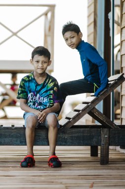 Semporna, Malezya - 25 Kasım 2019: Tahta sahil sandalyesinde oturan çocuklar.