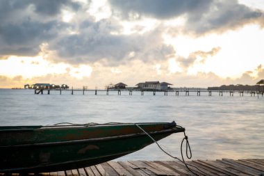 İskelede duran eski ahşap tekne güzel Semporna turkuaz denizine bakıyor..