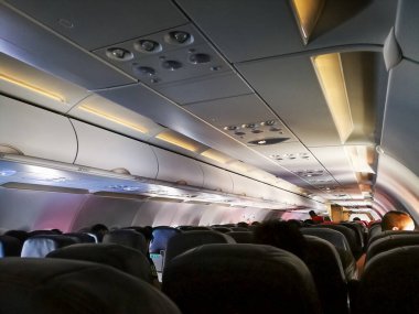 Kuala Lumpur, Malezya - 24 Kasım 2019: yolcu koltuğu, koltuklarda oturan yolcuların olduğu uçağın içi ve arka planda yürüyen hostes. Seyahat kavramı.