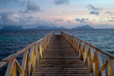 Borneo Sabah Semporna 'daki Bum bum adasının yakınındaki günbatımında tahta köprü..