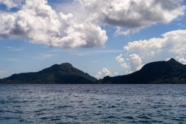 Kutlamalar deniz yüzeyi yaz dalgaları arka planı. Ufukta bulutlu ve adalı egzotik su manzarası. Doğal tropik su cenneti. Semporna doğa rahatla. Tropikal ada tatil beldesi. Okyanus doğası sükuneti.
